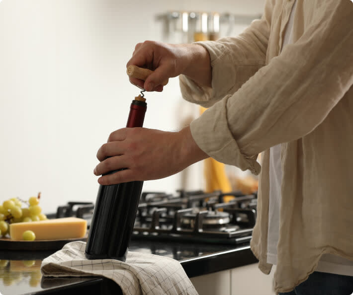 A person opening a bottle of red wine with a corkscrew; how to serve Chianti wine