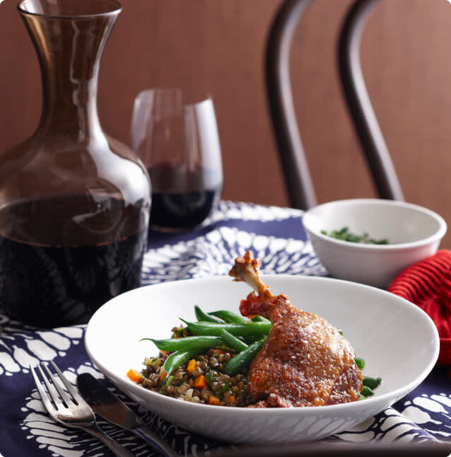 French duck confit served with red wine in a decanter and glass