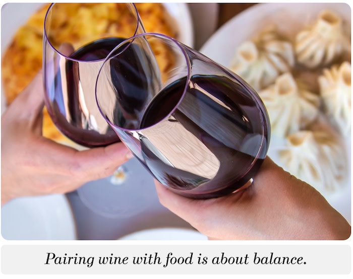 Two hands toasting with glasses of red wine over the dinner table