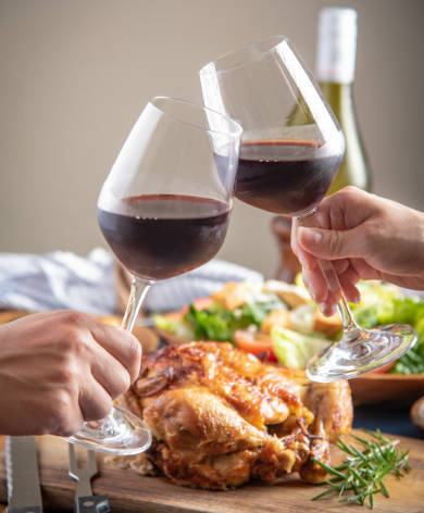  Couple holding each holding a glass of Pinot Noir with a roast chicken dinner