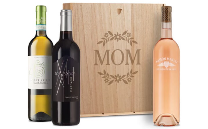 An image of 3 bottles of wine, one white, one red, and one rosé, next to an engraved wooden gift box inscribed with the word "MOM"