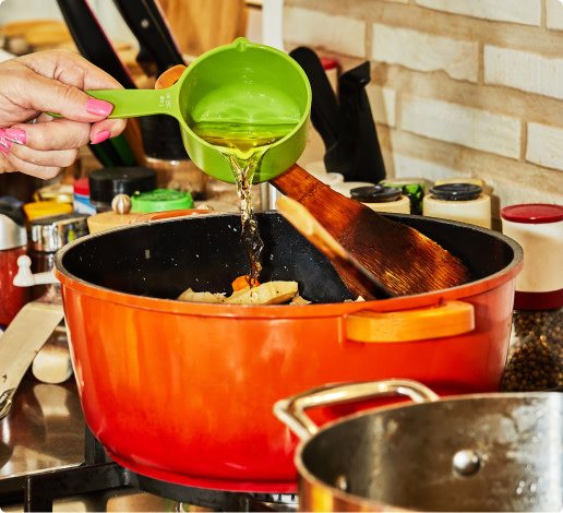Pouring a cup of white wine into a cooking pot