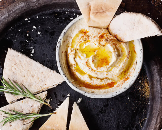 A plate of pita bread wedges served with a bowl of hummus