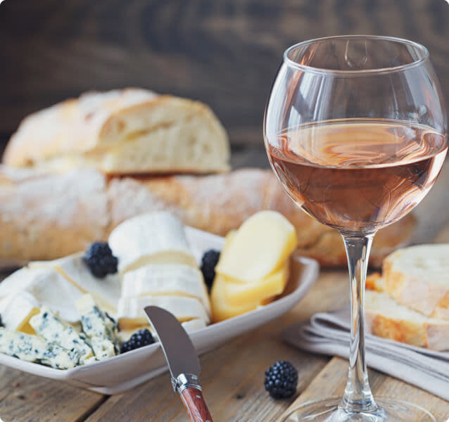 French cheeses and bread next to a glass of rosé wine