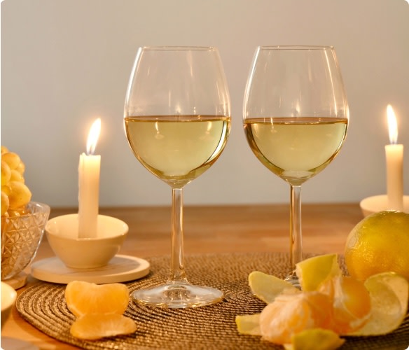 Two glasses of white wine at the dinner table with candles; perfect wines for Hanukkah parties