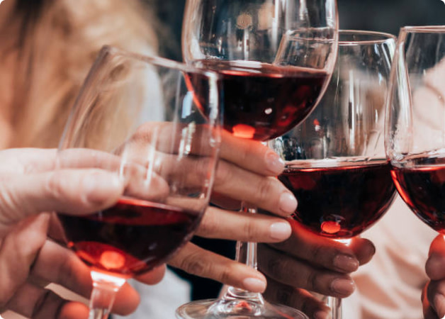 Hands holding glasses full of pinot noir wine