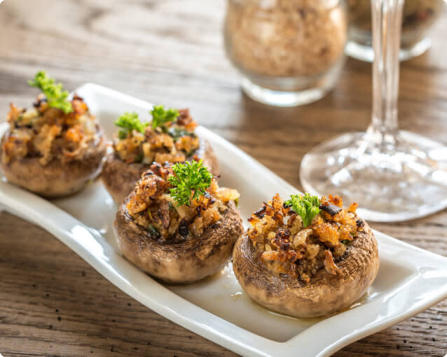 Vegetarian or vegan stuffed mushrooms on a small plate next to a wine glass