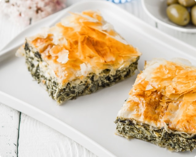 Two square slices of spanakopita on a white plate