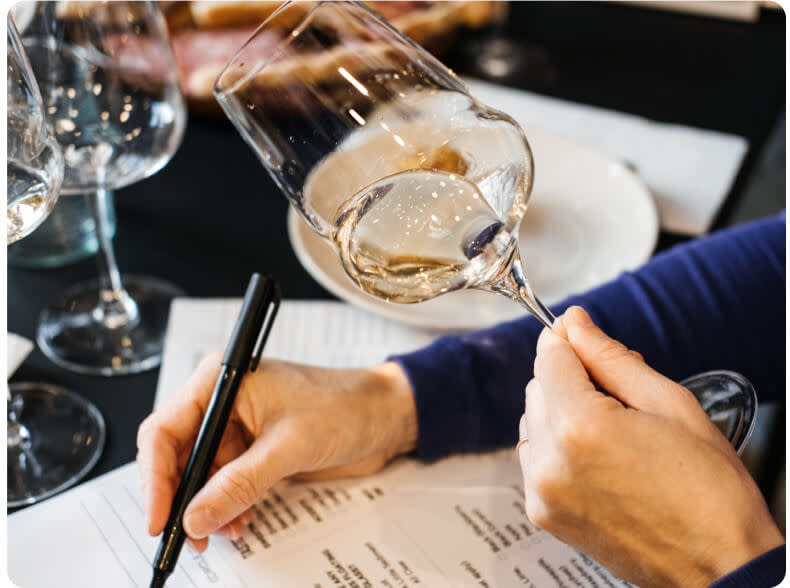writing down tasting notes of a glass of white wine
