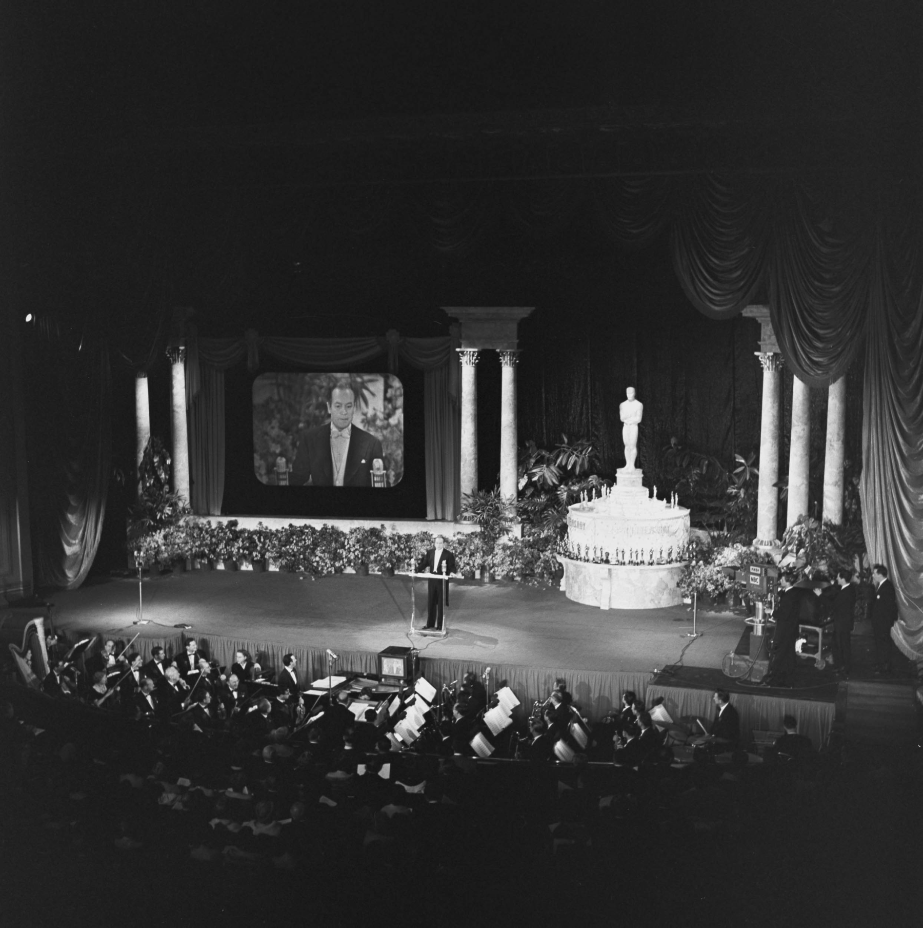 Master of ceremonies Bob Hope in front of the audience at the RKO Pantages Theatre during the 1952 Academy Awards, the first televised ceremony, evidenced by the NBC camera and simulcast screen visible on stage 

Courtesy of Academy Awards show photographs, Margaret Herrick Library, Academy of Motion Picture Arts and Sciences 