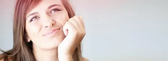 Bild på en ung kvinna som ser fundersam ut. Bilden illustrerar att det är vanligt att ha många frågor i samband med puberteten, om mens eller tamponger.