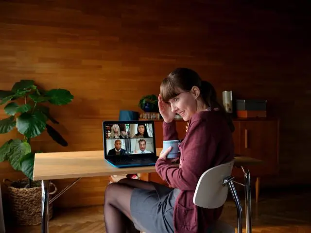 En kvinna i ett videosamtal som håller i en mugg och ser generad ut