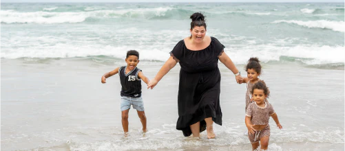 Woman and three children playing in the sea