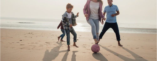 Family playing football on a beach