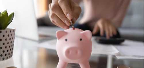 A coin being placed into a piggy bank