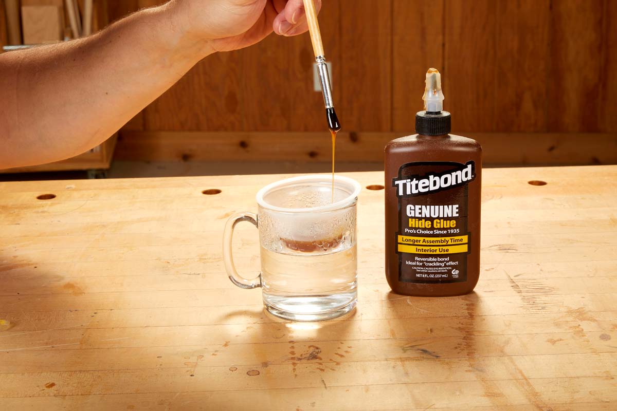 cup of titebond geniune hide glue with glue brush dripping glue back into cup, bottle of titebond genuine hide glue next to cup