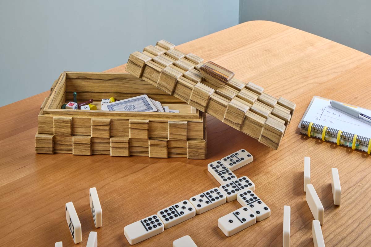 tiled treasure box open to reveal game pieces, dice, dominoes, cards