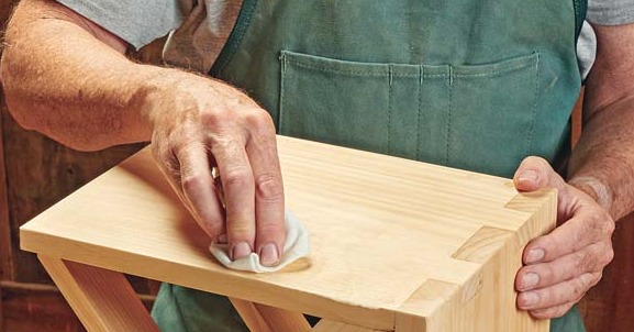 applying wax to wood project with cloth