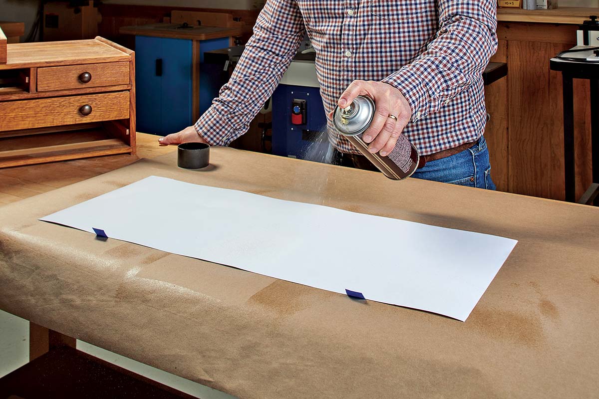 spraying down adhesive on posterboard