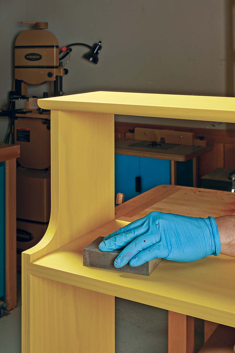 sanding the yellow painted bookshelf