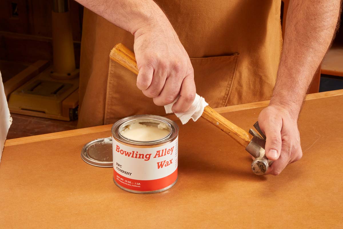 bowling wax being wiped onto wood handle of hammer