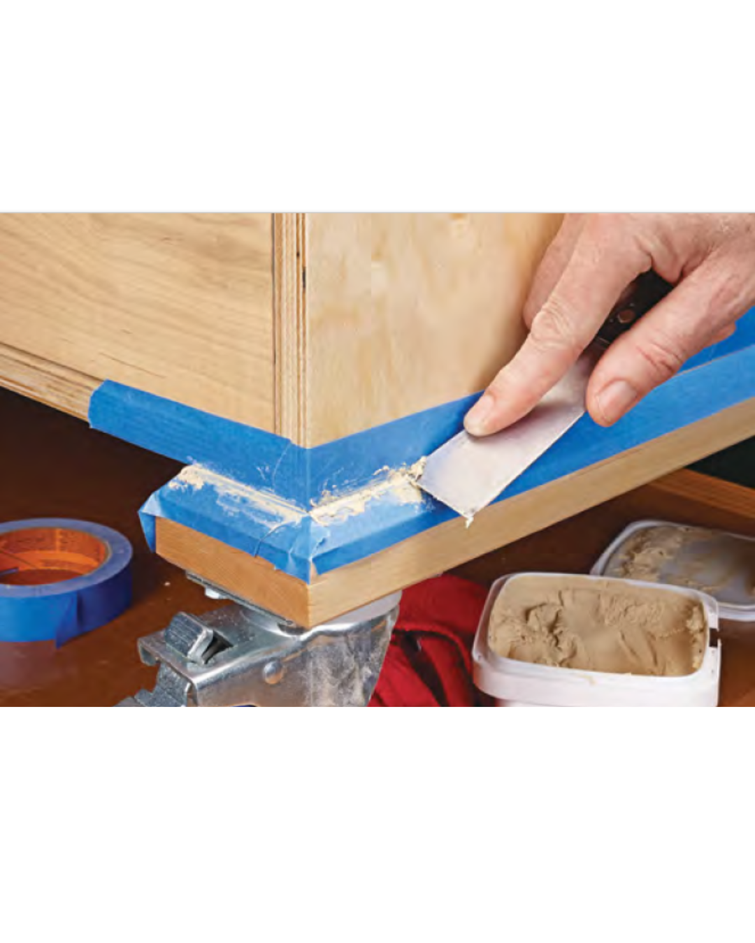 Image shows how to fill crack before sealing using wood filler, or wood putty, while using blue painters tape around the crack for accuracy