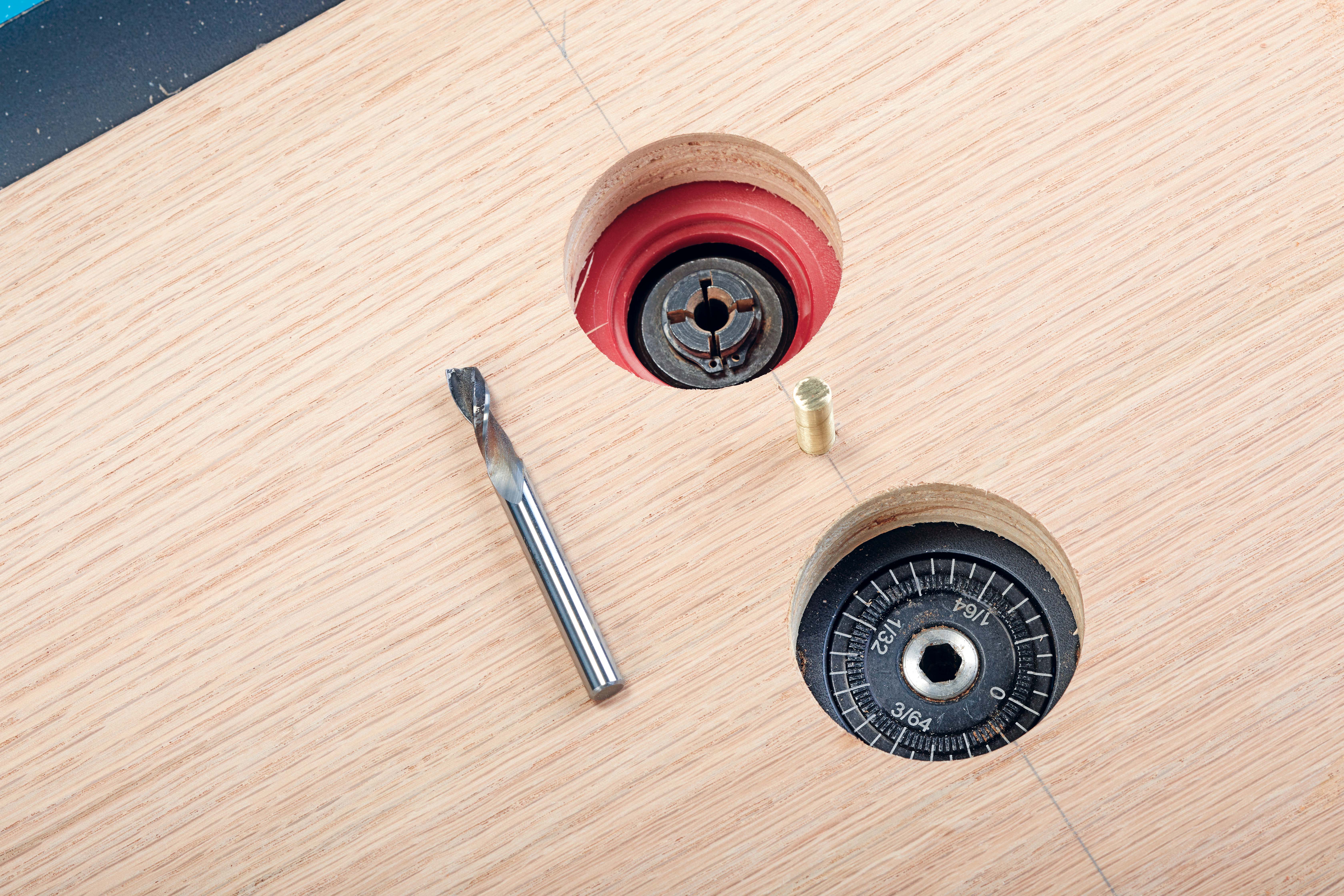 two holes made in wood for router bit and the bit height adjustment