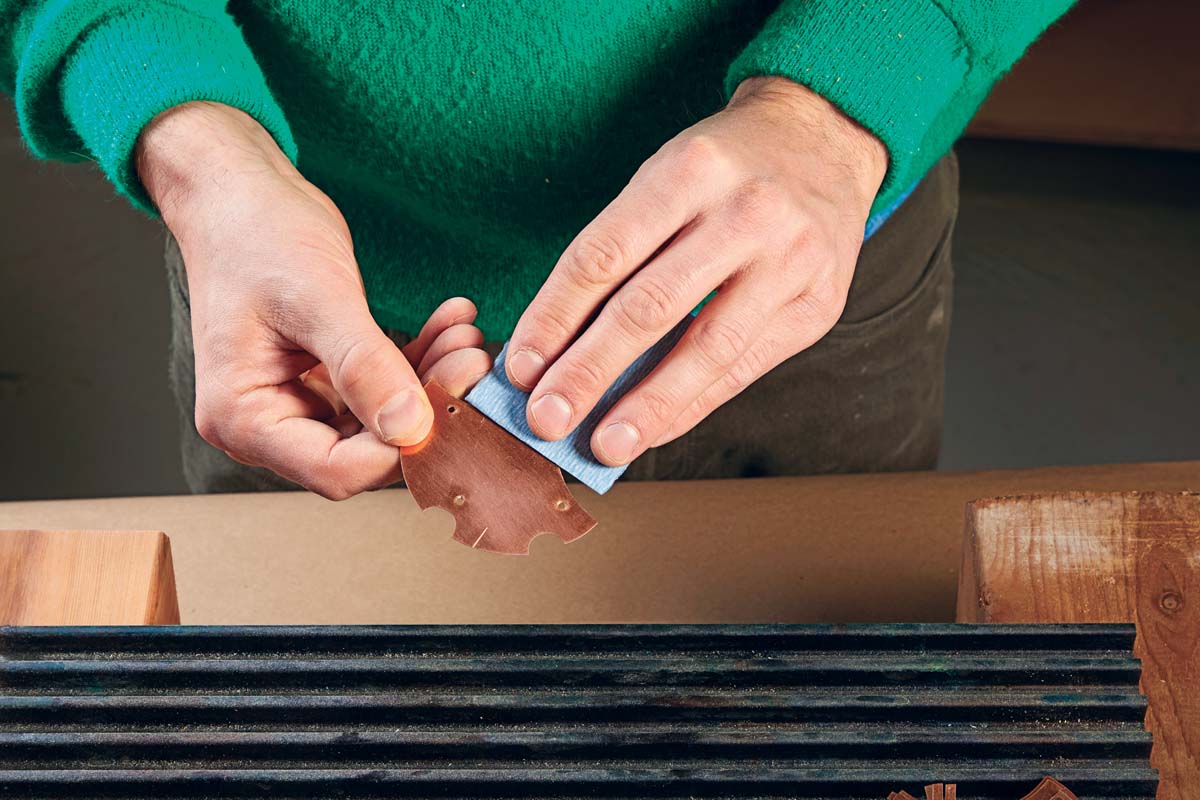 hands sanding copper with 400-grit sandpaper