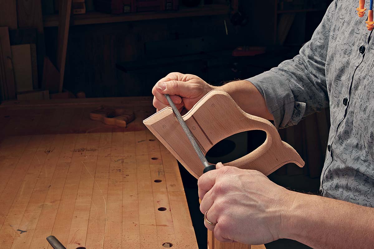 round file being used on curves of wooden saw handle