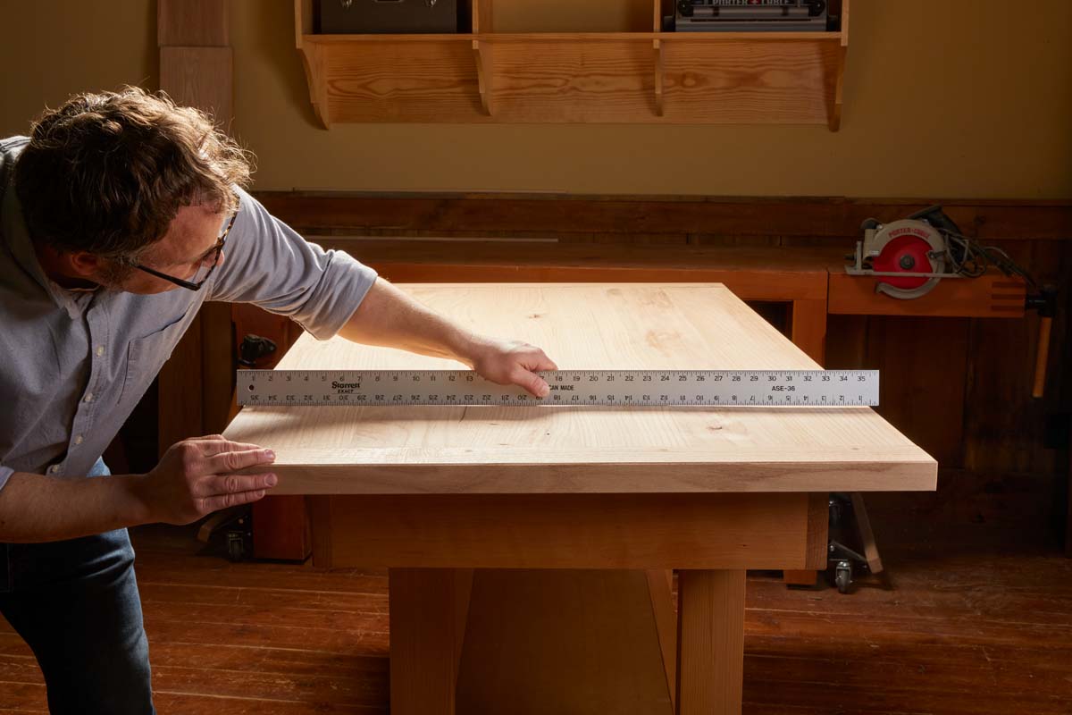 using long metal ruler to cast shadow and find uneven spots in table top