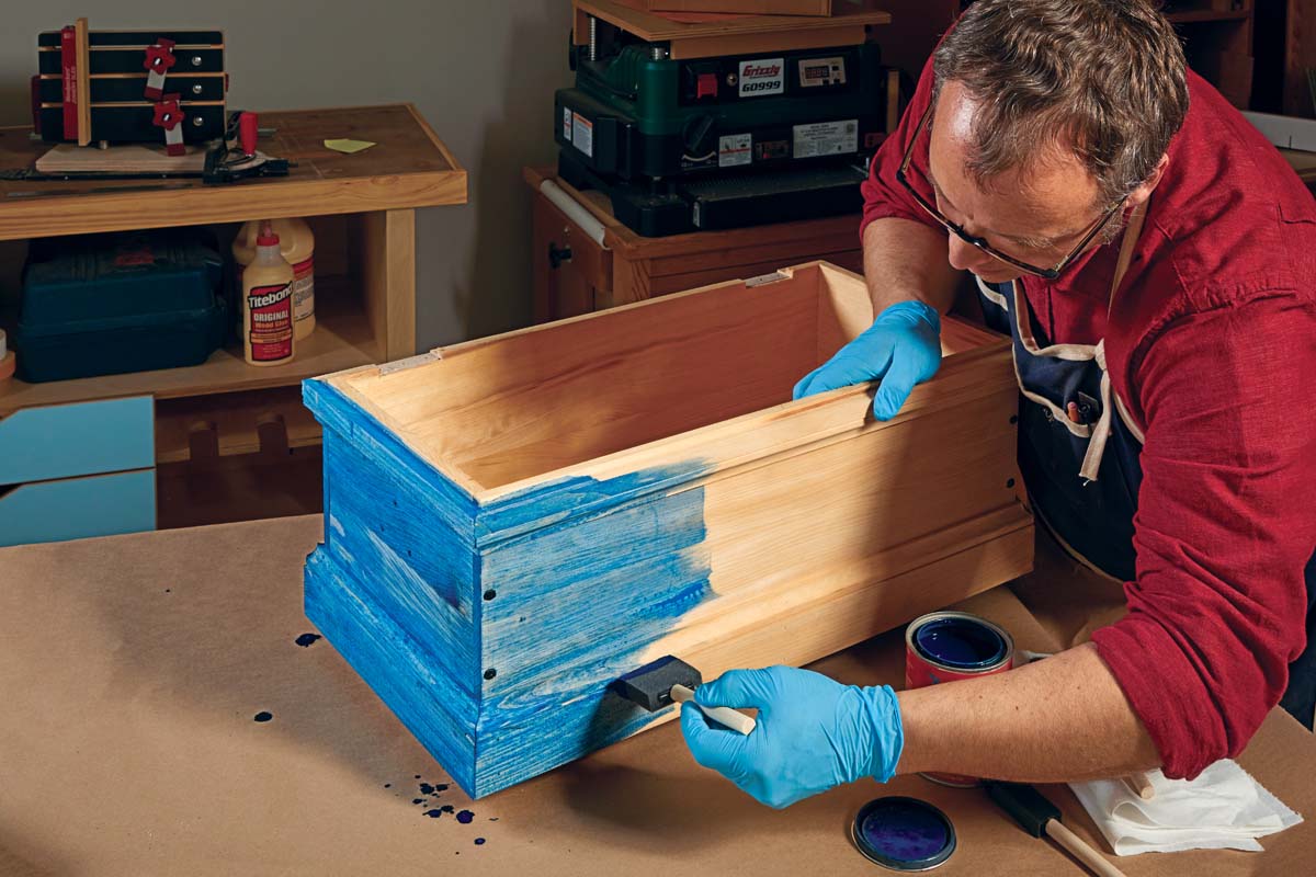 Phil Huber painting handmade wood box with blue water based paint dye using foam brush