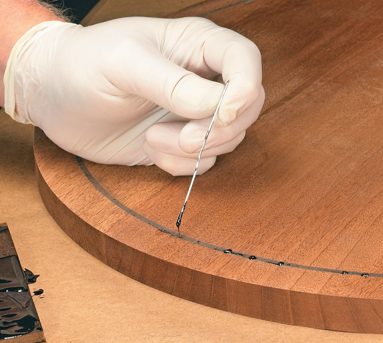 Using straightened paperclip to pop air bubbles in the inlay