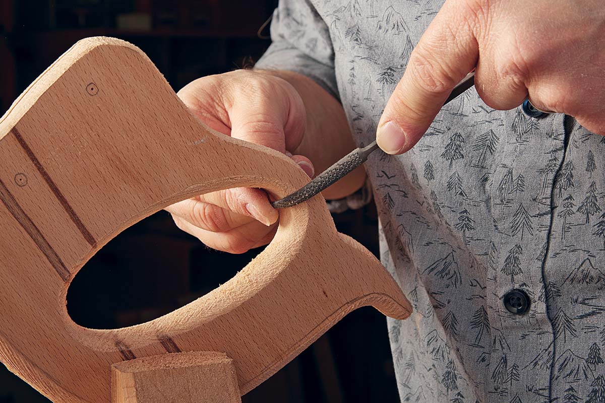 riffler being used to blend curves of wooden handle for saw