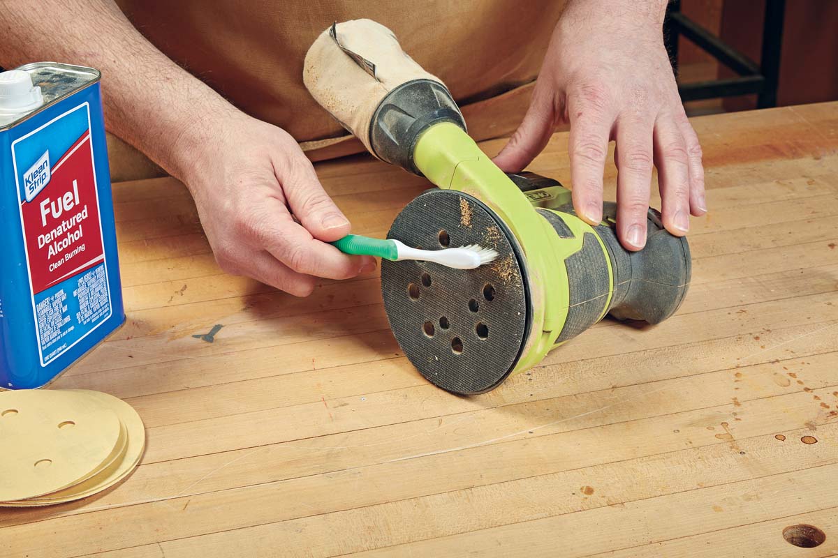using toothbrush to clean sanding pad