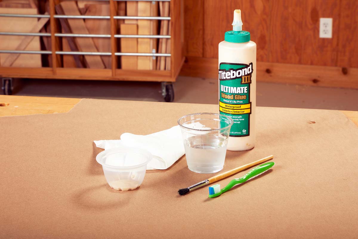 glue kit of titebond III ultimate wood glue, repurposed fruitcup with glue, small cup of water, a cloth, a glue brush and a toothbrush