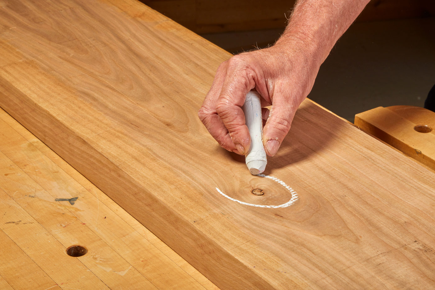 Using chalk to circle imperfections on the wood