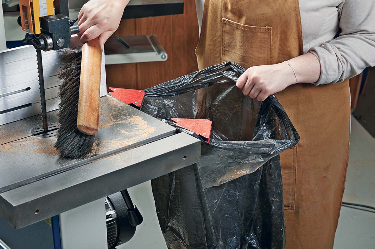 brushing off dust into trash bag held up by magnets