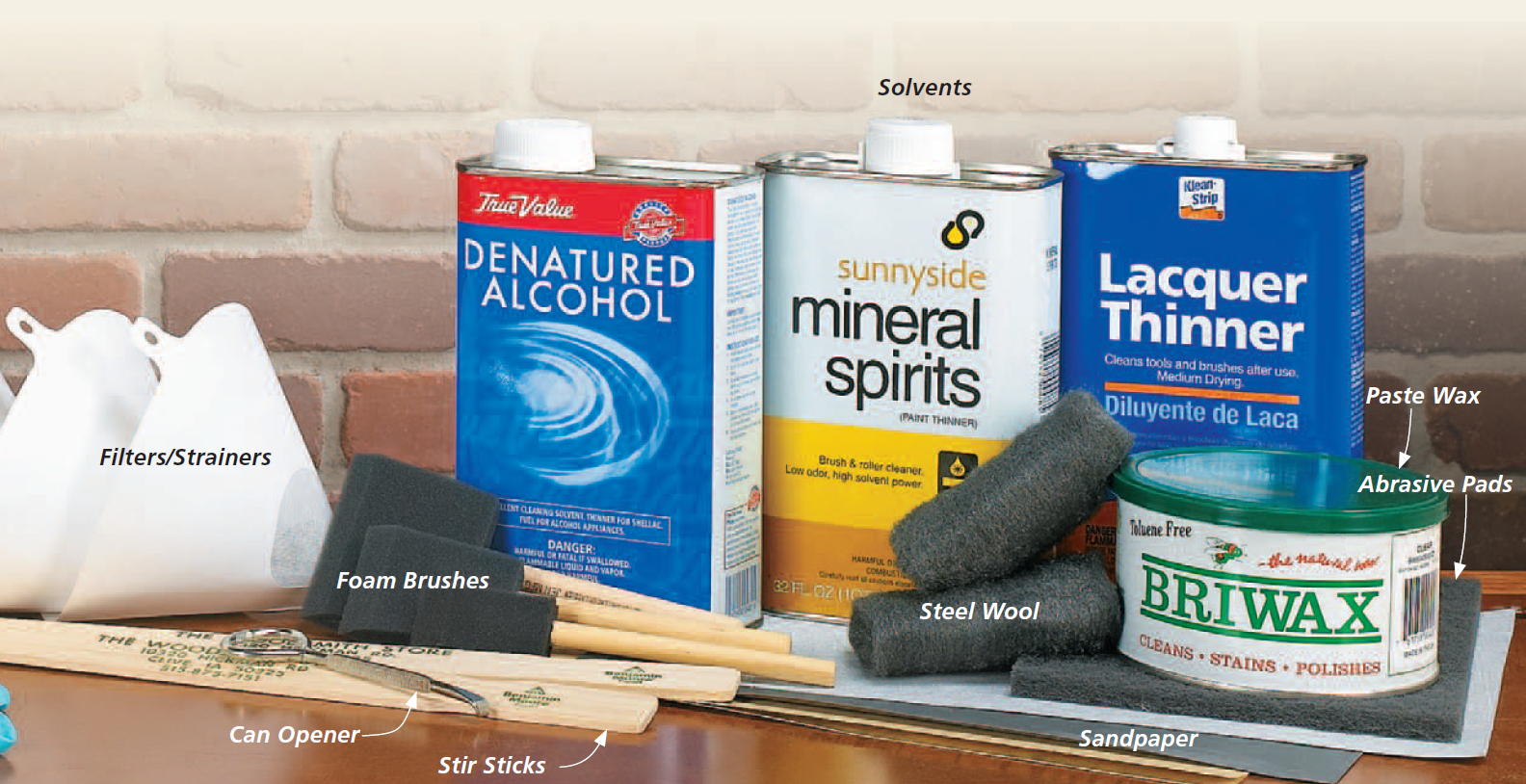 image of supplies for finishing includes denatured alchohol, mineral spirits, lacquer thinner, briwax, foam brushes, steel wool, stir sticks, filters and strainers, sandpaper, abrasive pads, and can opener