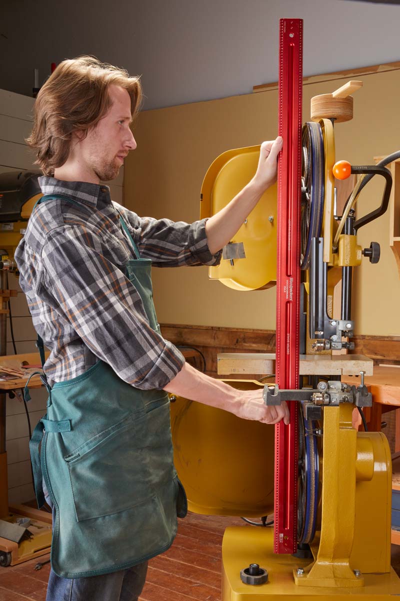using long metal ruler to check if band saw wheels are straight