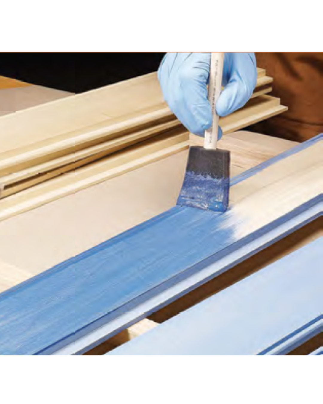Foam brush being used to spread blue paint on wood