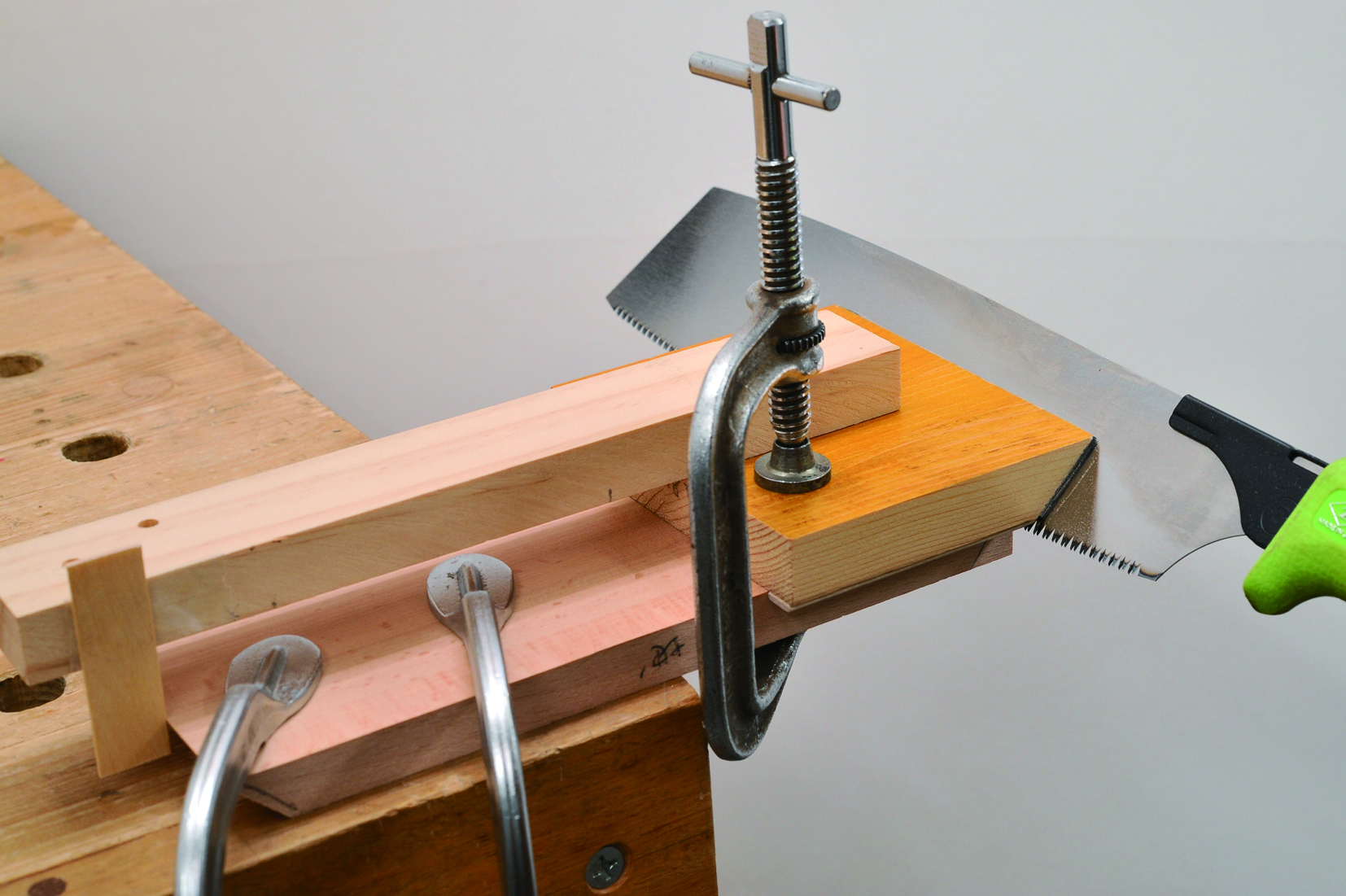 using hand saw on clamped piece of wood