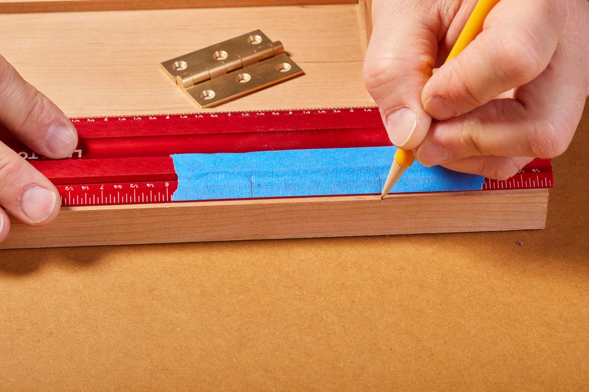 using metal ruler with blue masking tape and a pencil to mark where hinge goes