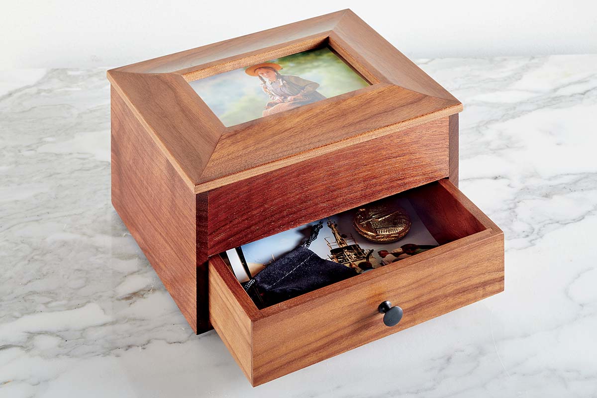 open drawer of wood memory box holding trinkets like photo or gold medal