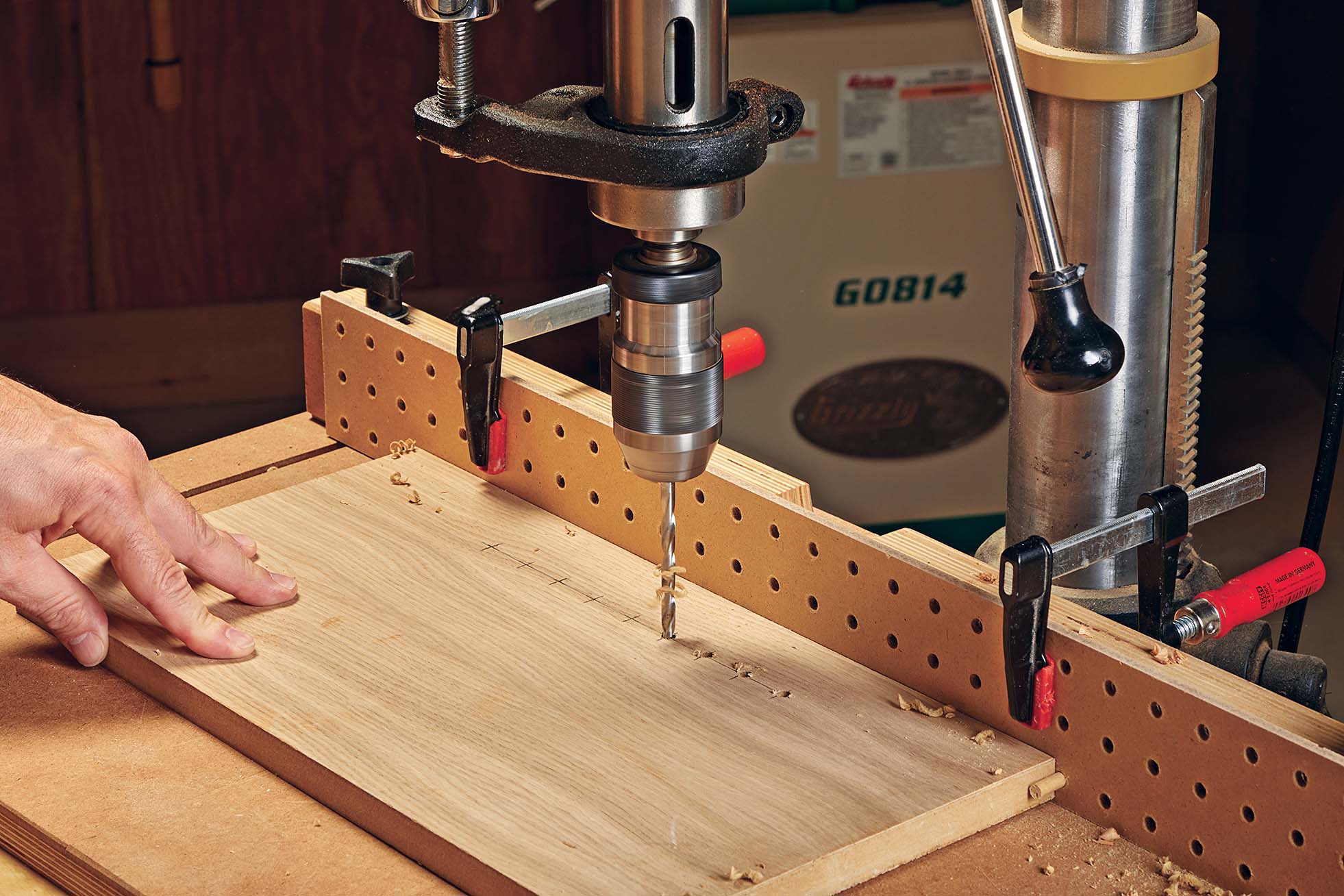 Pegboard being used as drill guide fence, with dowels in the pegs to save your spot