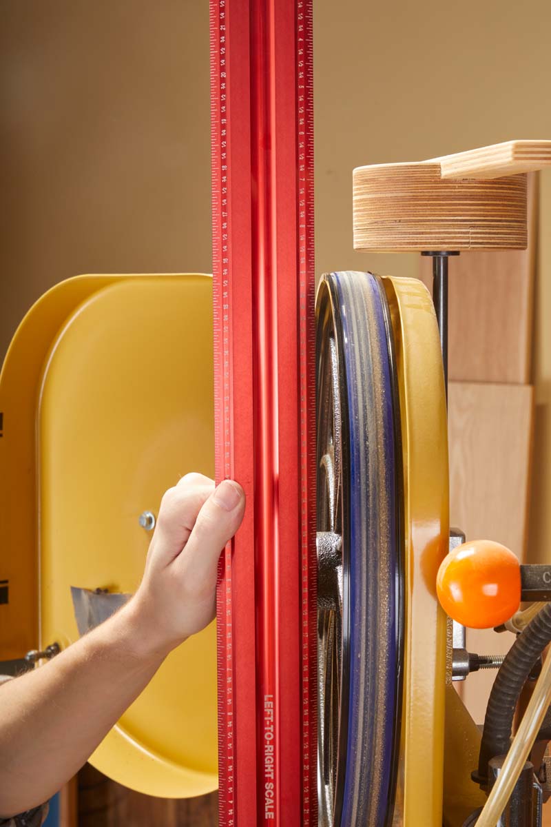 using long metal ruler to check if band saw wheels are straight close up