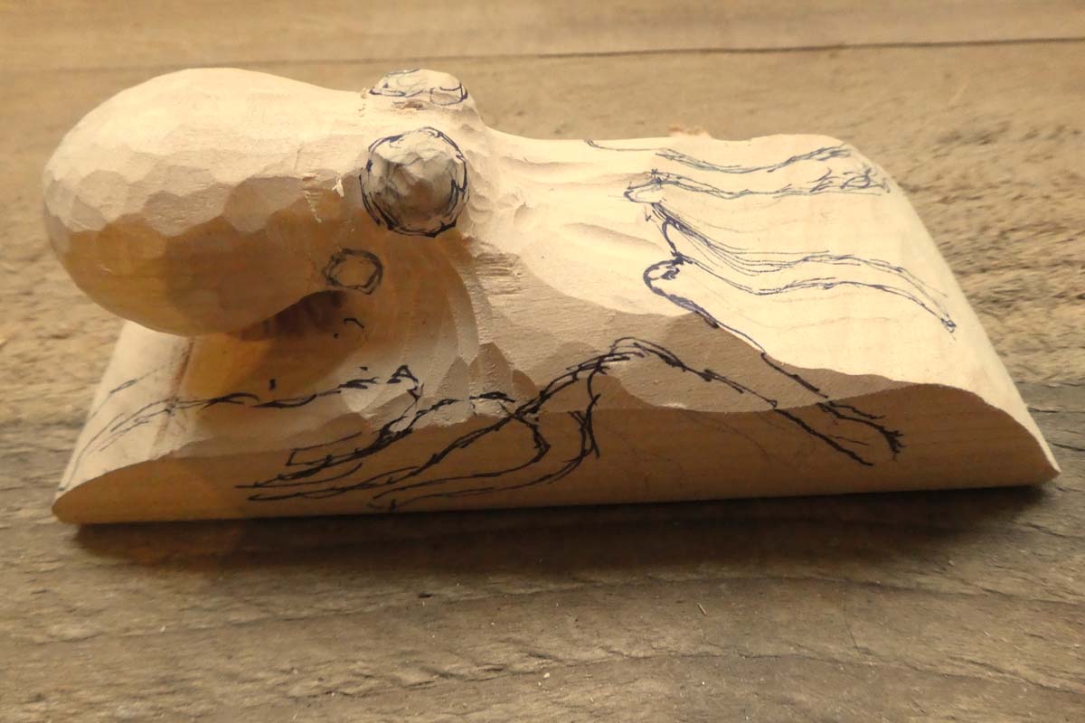 partially carved wooden octopus with added pencil marks for rest of eyes and tentacles