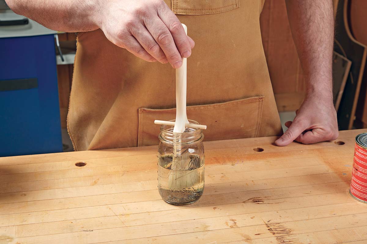 paint brush soaking in jar using dowel to hold it