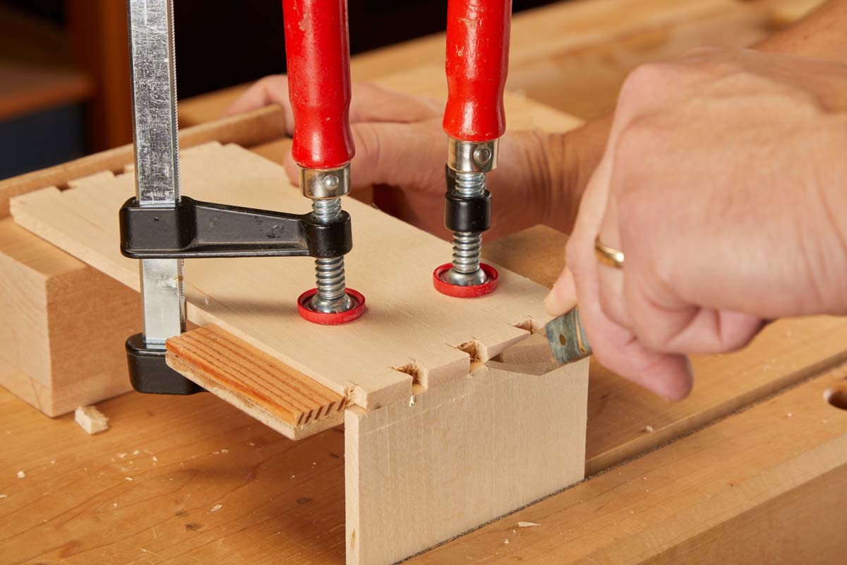 tracing sides of each dovetail on clamped pieces of wood, with a knife