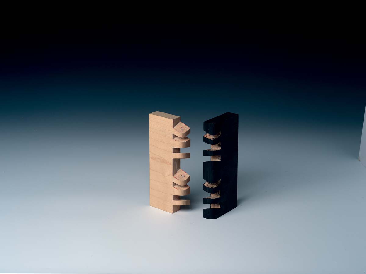 joinery example of double sunrise dovetail with one piece of wood painted black, both pieces not connected