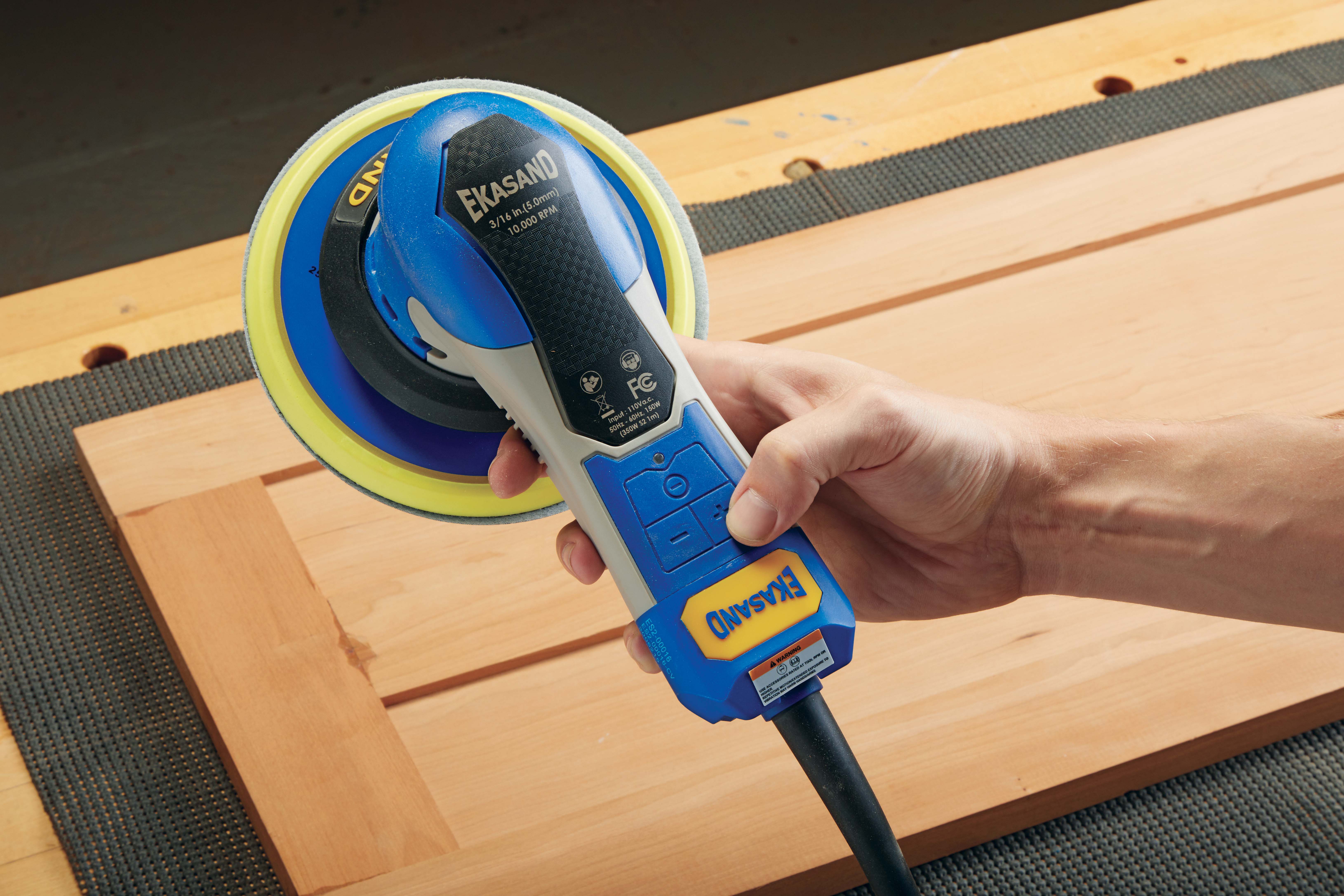 thumb pointing to buttons on the back of the Uneeda Ekasand Random 6 inch Orbit Sander